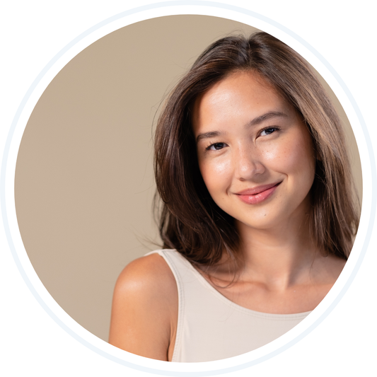 Asian woman in white tank top smiling in front of beige background
