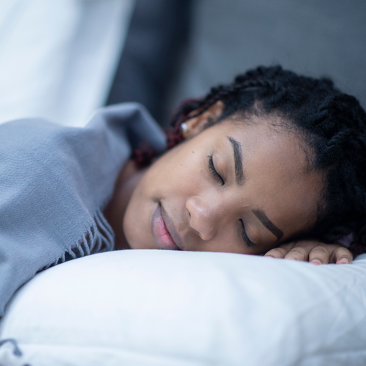 Woman sleeping peacefully with a soft smile on her face, wrapped in a light blue blanket.
