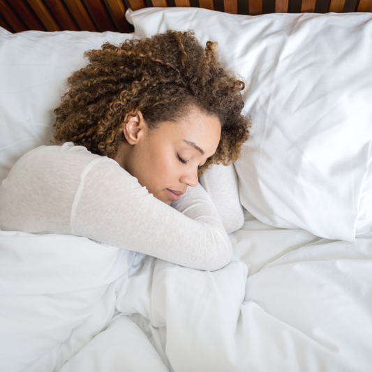 Woman sleeping with a white pillow and blanket in a bedroom setting